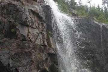 a large waterfall next to a rock