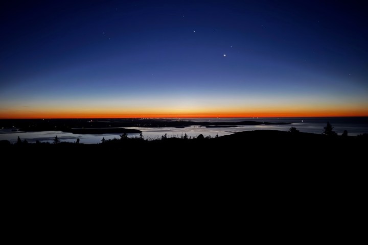 Twilight sky over a calm sea with a gradient from deep blue to orange on the horizon.
