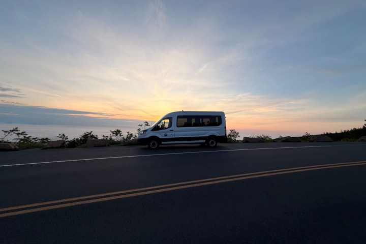 Van parked by roadside at sunset with clear sky and faint clouds.